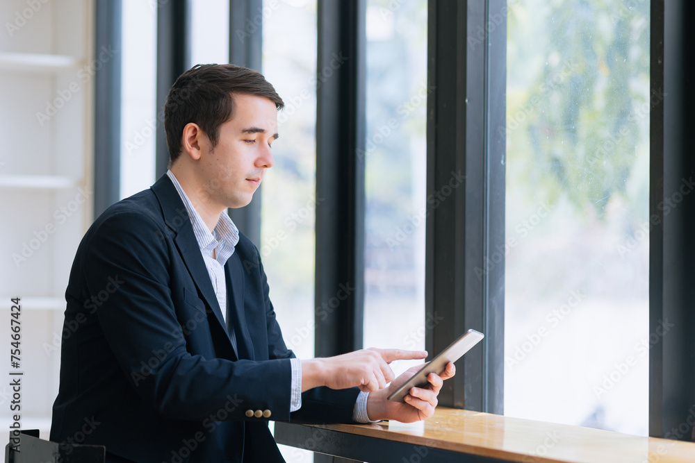 Businessman using tablet sitting at desk in office. Businessman using tablet sitting at desk in office.