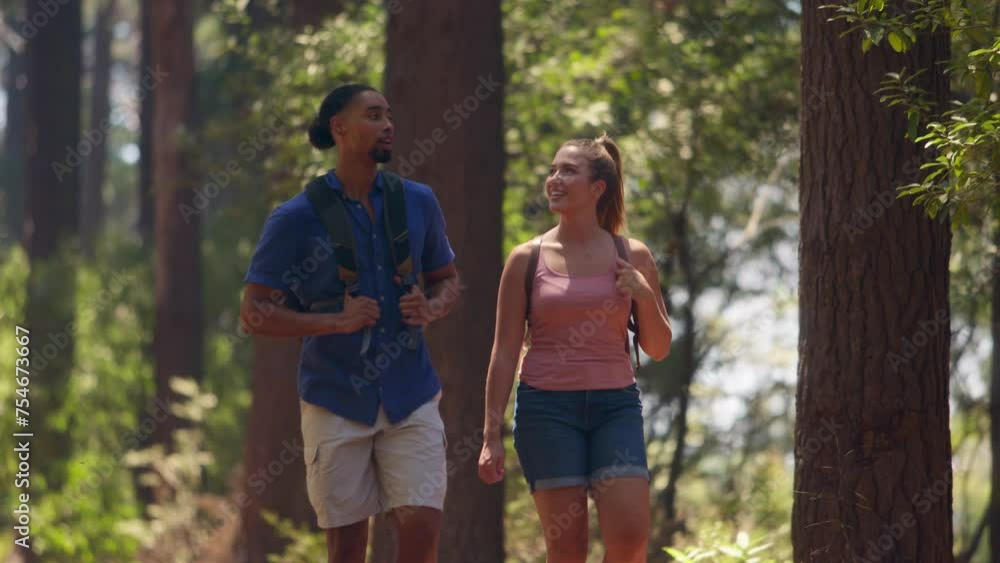 Young active couple wearing backpacks hiking along trail through summer countryside - shot in slow motion Young active couple wearing backpacks hiking along trail through summer countryside - shot in slow motion