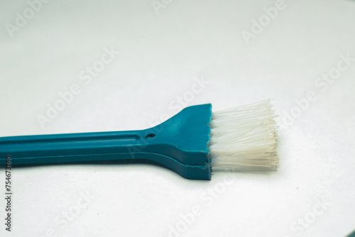 A small blue dust cleaning brush with white bristles