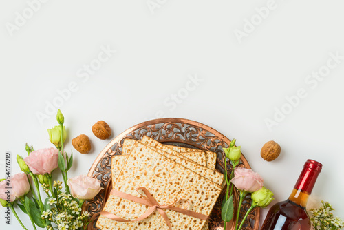 Jewish holiday Passover concept with matzah, seder plate, spring flowers and wine bottle on white  background. Top view, flat lay