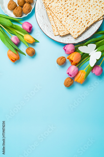 Jewish holiday Passover vertical greeting card with matzah and  spring tulip flowers on blue  background. Top view, flat lay composition