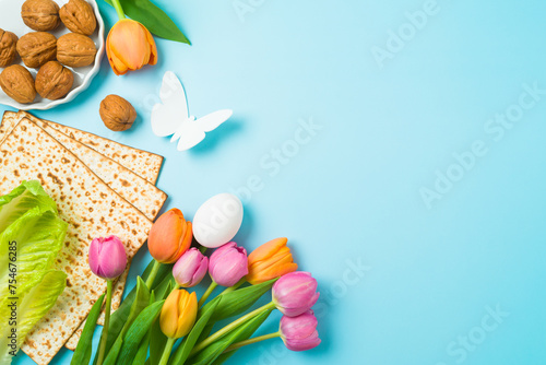 Jewish holiday Passover concept with matzah and  spring tulip flowers on blue  background. Top view, flat lay composition