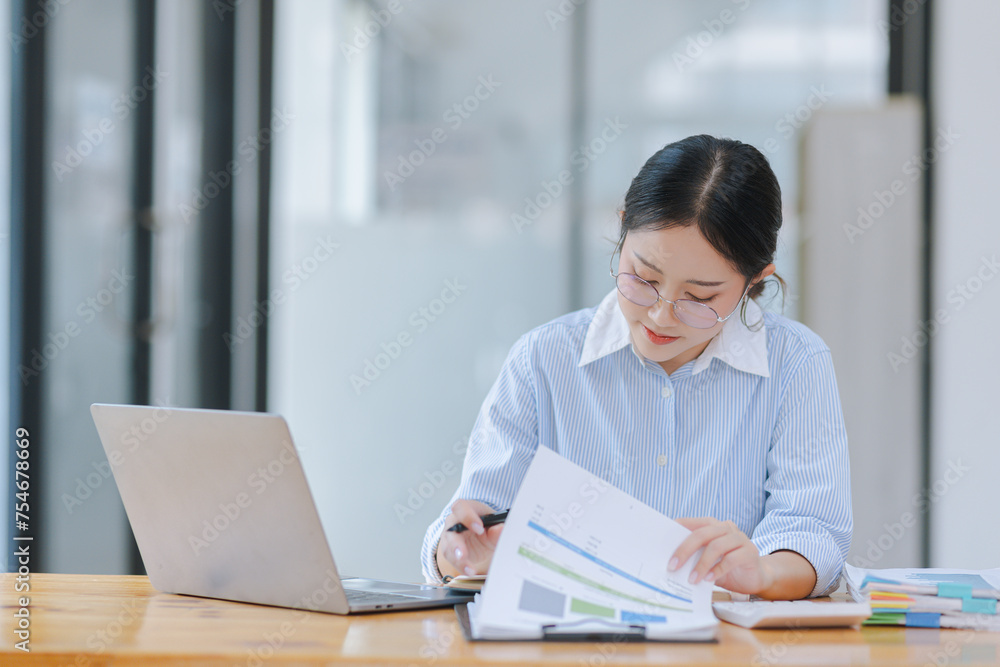 Asian accounting woman working with document paper and laptop computer at table office, Financial and accounting woman concept. Asian accounting woman working with document paper and laptop computer at table office, Financial and accounting woman concept.