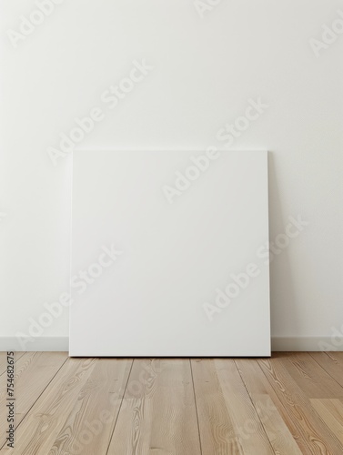 A blank canvas model leans against the white walls of a modern minimalist wood floor. 