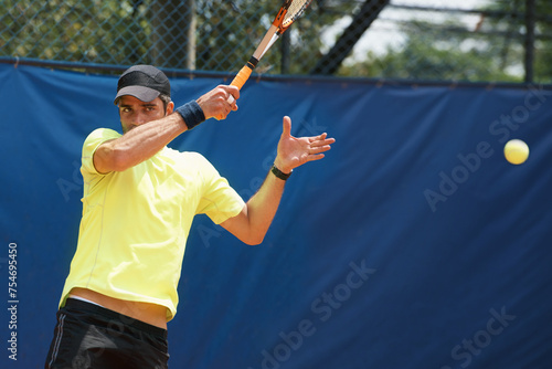 Man, serve and playing in competition on tennis court, athlete and racket or ball for professional match. Fitness, outdoor and person in training for tournament and skill of champion player in game © Katie/peopleimages.com