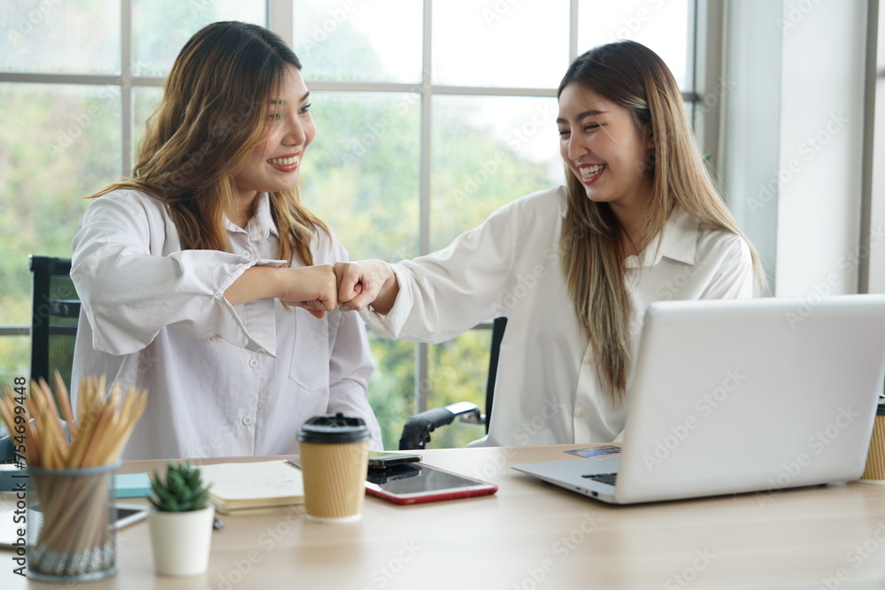 Two young Asian women roommates working at home with laptops and hand bump together with friends smiling, happy at successful online business apartment. Two young Asian women roommates working at home with laptops and hand bump together with friends smiling, happy at successful online business apartment.