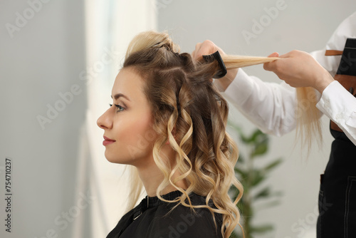 Hair styling. Professional hairdresser combing woman's hair in salon, closeup