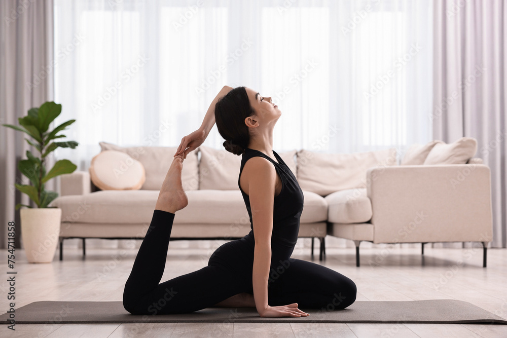 GIrl practicing one legged king pigeon asana on yoga mat at home. Eka pada rajakapotasana pose GIrl practicing one legged king pigeon asana on yoga mat at home. Eka pada rajakapotasana pose