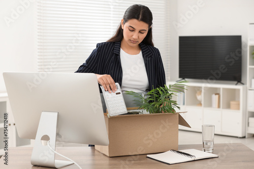 Unemployment problem. Woman with box of personal belongings at table in office