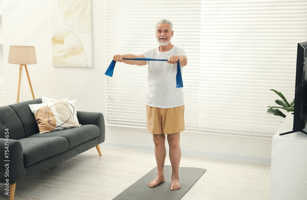 Senior man doing exercise with fitness elastic band on mat at home Senior man doing exercise with fitness elastic band on mat at home