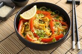 Stir-fry. Delicious cooked noodles with chicken and vegetables in bowl served on table, closeup