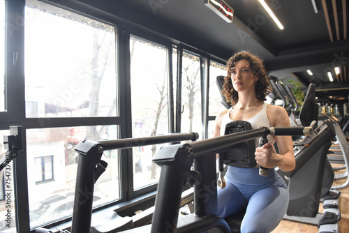 Fit woman training on row machine in gym. Sport, fitness, lifestyle and people concept