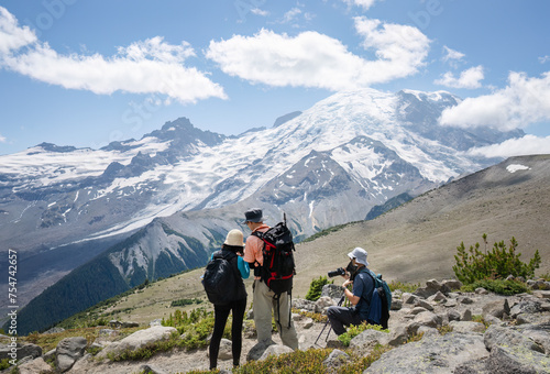 Three people hiking the Sunrise Trail. Mt Rainier in the background. Mt Rainier National Park. Washington State.