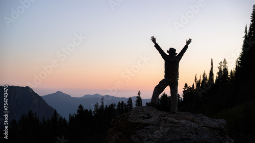 Silhouette image of a man raising arms at sunset. Paradise. Mount Rainier National Park. Washington State. USA.
