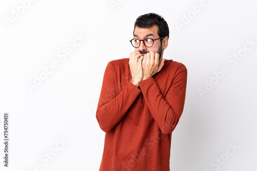 Caucasian handsome man with beard over isolated white background nervous and scared putting hands to mouth