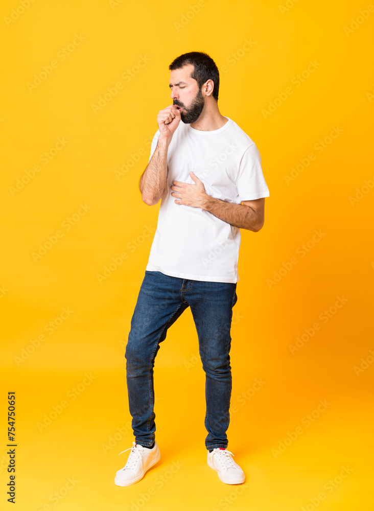 Full-length shot of man with beard over isolated yellow background is suffering with cough and feeling bad Full-length shot of man with beard over isolated yellow background is suffering with cough and feeling bad