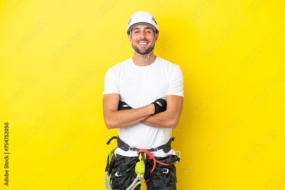 Young rock- climber man isolated on yellow background keeping the arms crossed in frontal position Young rock- climber man isolated on yellow background keeping the arms crossed in frontal position