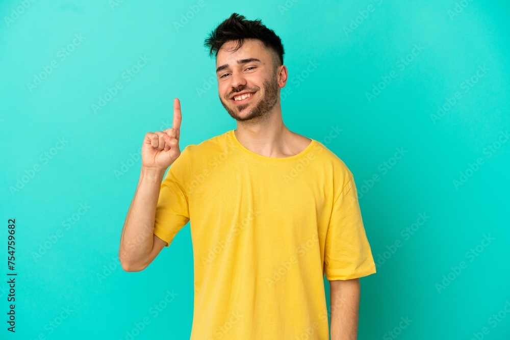Young caucasian man isolated on blue background showing and lifting a finger in sign of the best Young caucasian man isolated on blue background showing and lifting a finger in sign of the best
