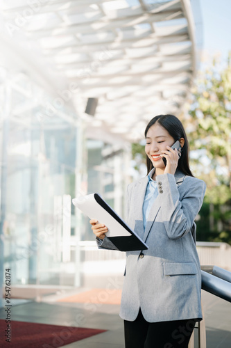 Asian business woman leader entrepreneur, professional manager holding digital tablet computer uon the street in big city on business center background. photo