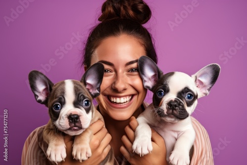 Joyful woman with two adorable French Bulldog puppies on a purple background © Georgii
