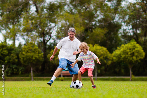 Father and son play football. Dad and kid run.