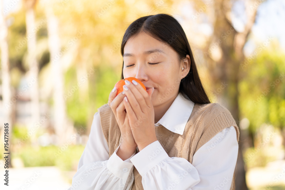 Pretty Chinese woman at outdoors holding an orange Pretty Chinese woman at outdoors holding an orange