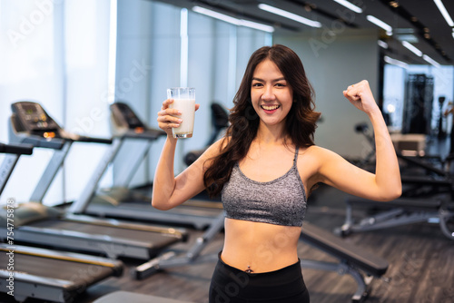 Attractive fitness asian woman finishing workout and drinking protein milk shake vitamins after training. Bodybuilding. Healthy lifestyle.