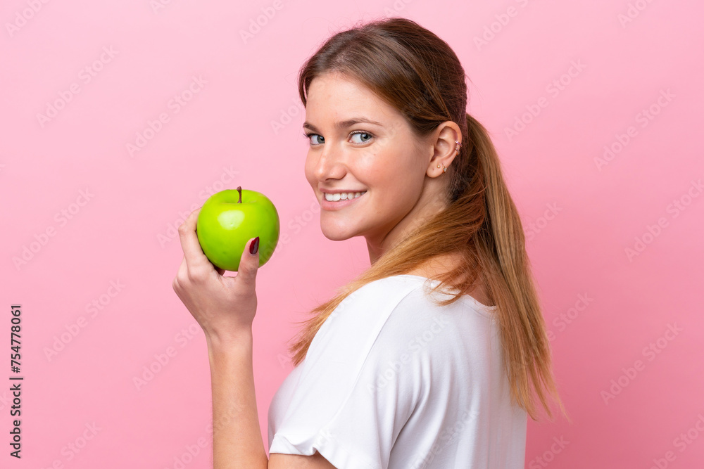 Young caucasian woman isolated on pink background eating an apple Young caucasian woman isolated on pink background eating an apple