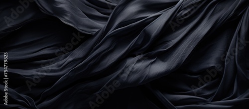 A dark black cloth is draped on a black background, creating a sense of depth and contrast in the image. The texture of the fabric is prominently displayed against the dark backdrop.