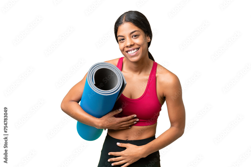 Young sport African American woman going to yoga classes while holding a mat over isolated background smiling a lot Young sport African American woman going to yoga classes while holding a mat over isolated background smiling a lot