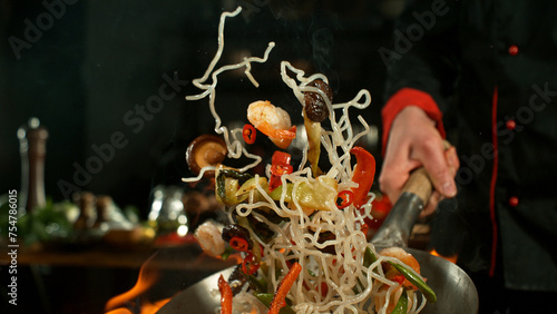 Freeze motion of flying asian wok noodles with prans and vegetable. The concept of meat preparation.