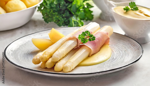 White asparagus with ham, hollandaise sauce and potatoes on the plate