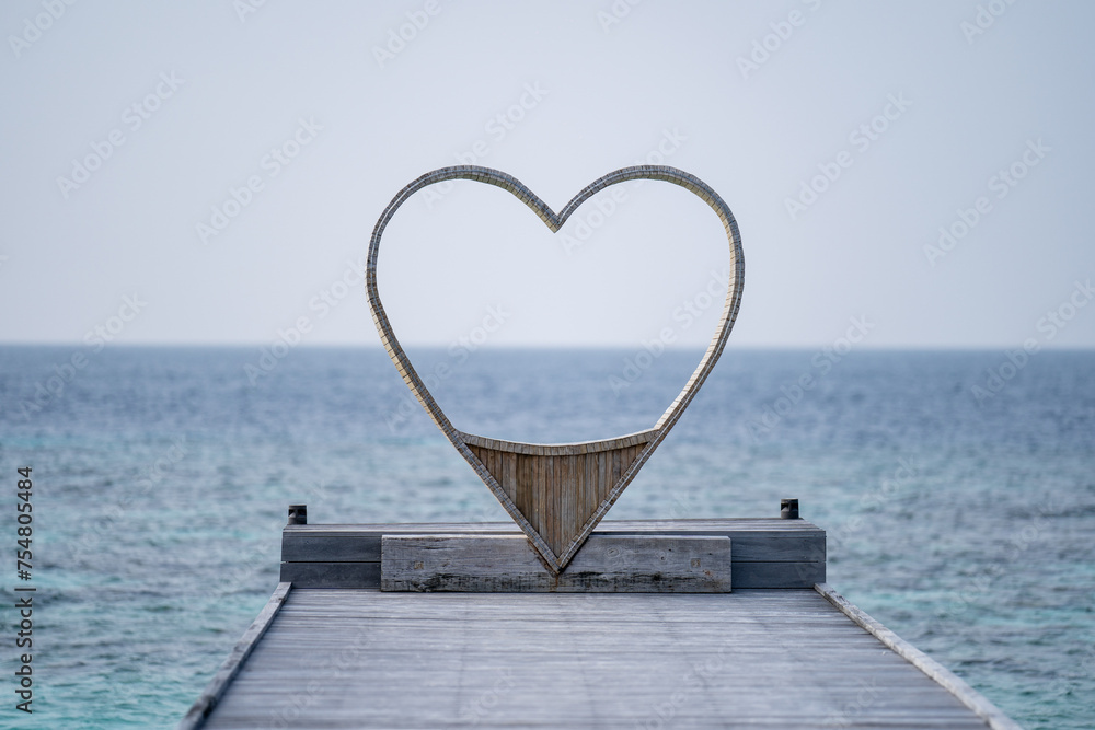 Wooden heart shaped chair looking through the sea  for couple, ocean background.