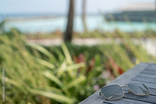 Sunglasses on wooden table on tropical beach background.