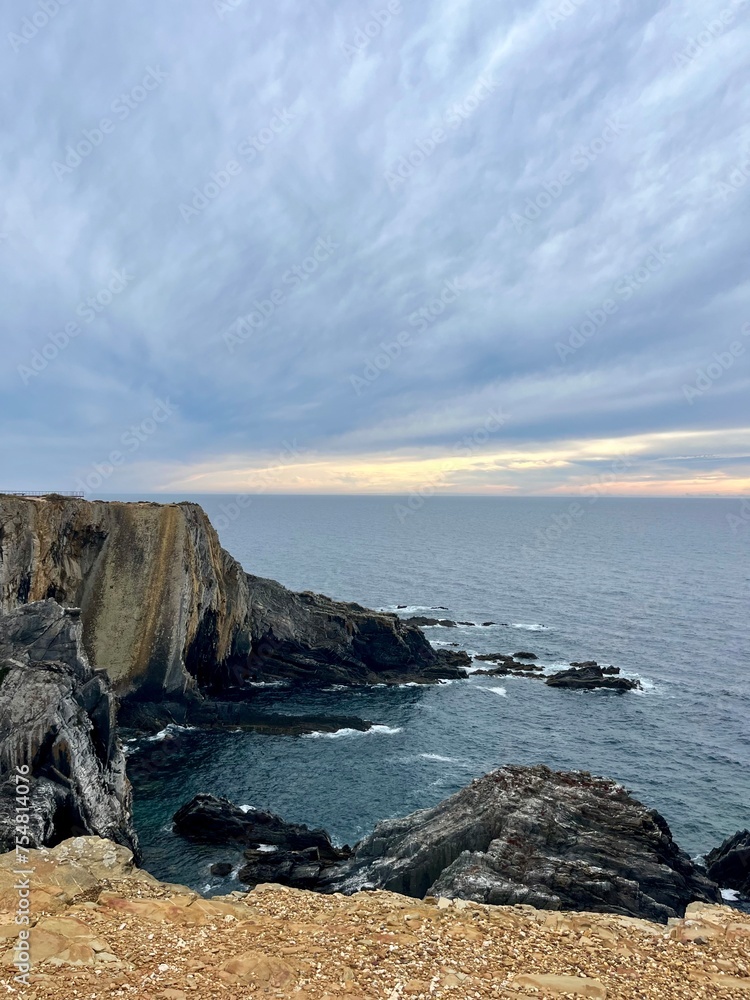 Fantastic rocky coast, cloudy sky, twilights time, ocean horizon Fantastic rocky coast, cloudy sky, twilights time, ocean horizon