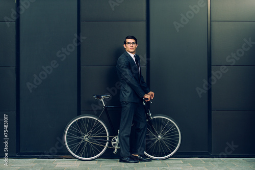 Handsome young business man wearing elegant corporate suit going to work with bicycle, concepts of transportation, green mobility and eco friendly lifestyle © oneinchpunch