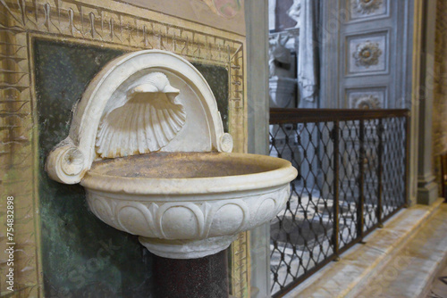 Inlaid marble holy water font and ancient romanesque church photo