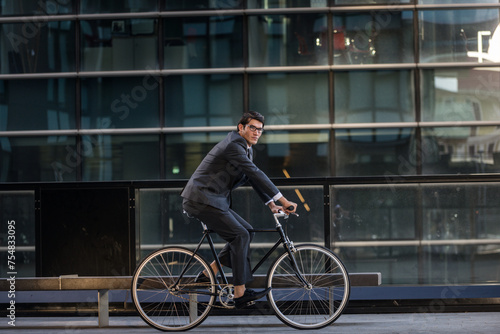 Handsome young business man wearing elegant corporate suit going to work with bicycle, concepts of transportation, green mobility and eco friendly lifestyle