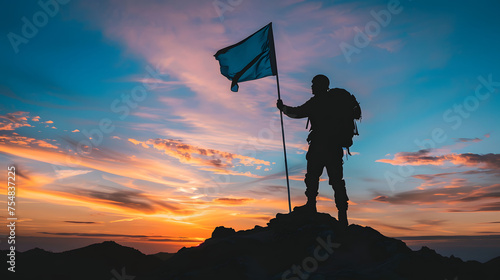 A man stands on a snow-covered mountain peak, holding a blue flag. The sun shines brightly in the background.