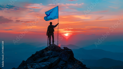 A man stands on a snow-covered mountain peak, holding a blue flag. The sun shines brightly in the background.