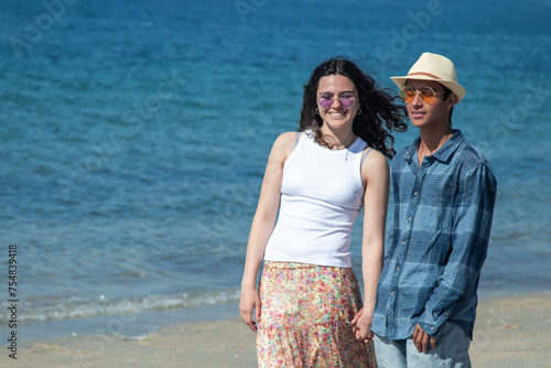 young couple walking hand in hand on the beach photo