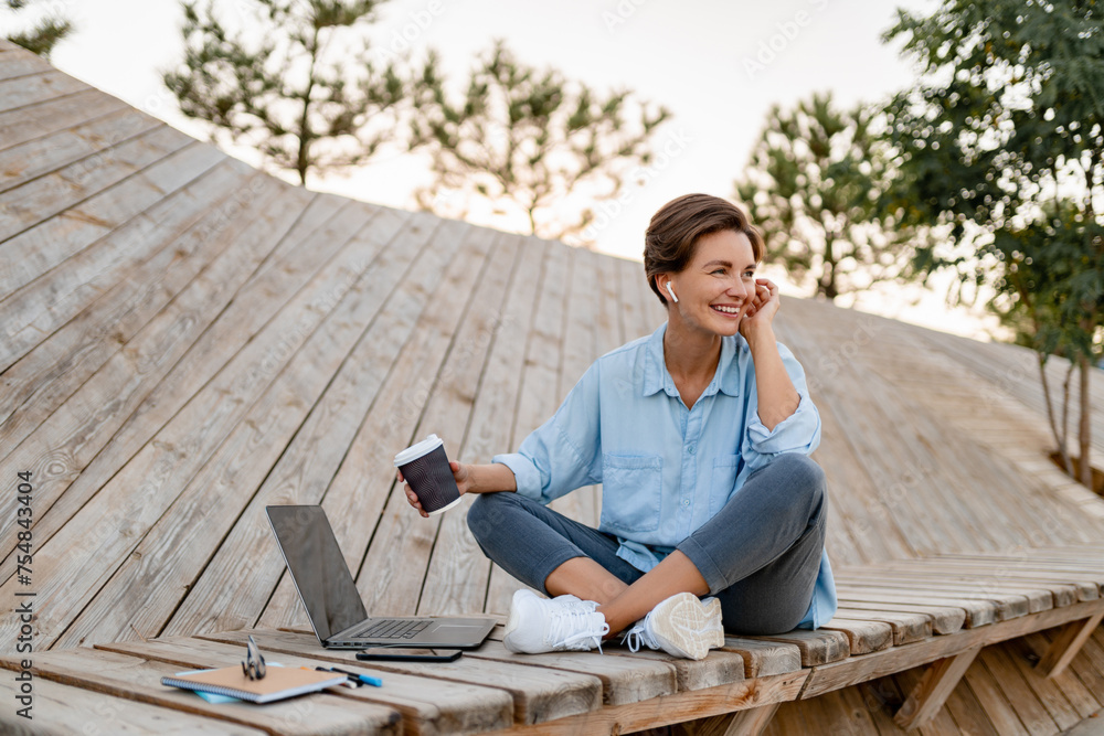 young pretty woman working on laptop in modern park street