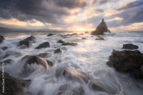 The sea water enters forcefully between the rocks of the shore on a warm sunset on the beach of Meñakoz, Sopelana, Bizkaia photo