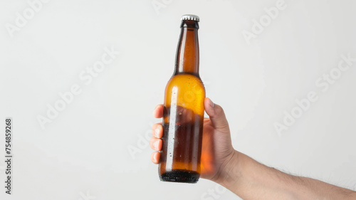 A hand holding a cold beer bottle with a dewy surface against a minimalistic background.