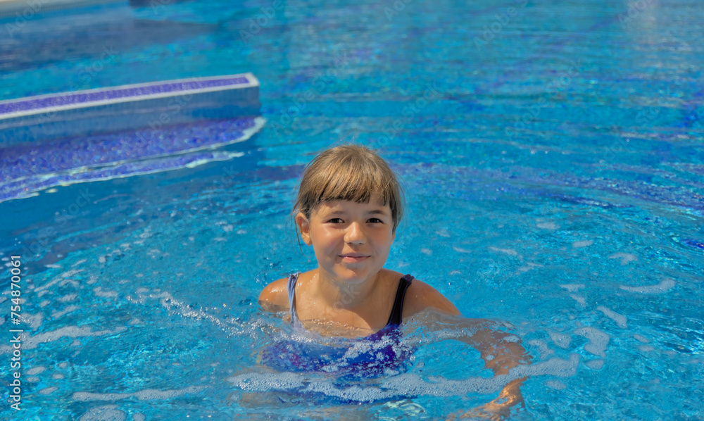 A joyful child happily swimming and enjoying leisure time in an open pool with clear blue water. Active summer recreation in a resort with a swimming pool, embodying the essence of a happy childhood.
