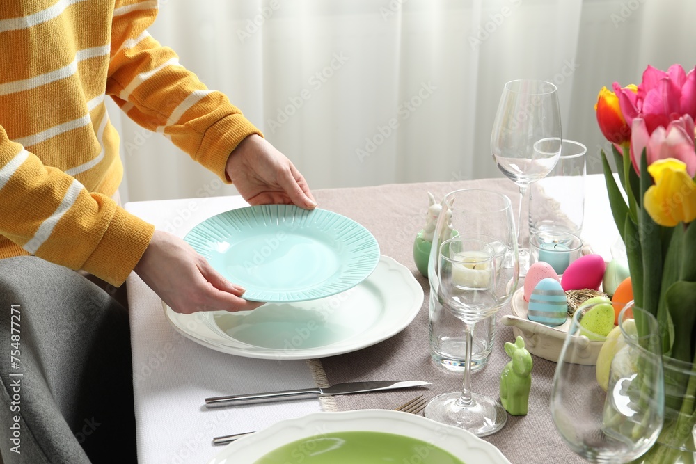 Woman setting table for festive Easter dinner at home, closeup Woman setting table for festive Easter dinner at home, closeup