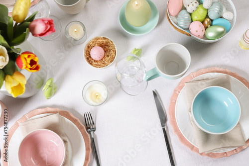 Festive table setting with painted eggs, flat lay. Easter celebration