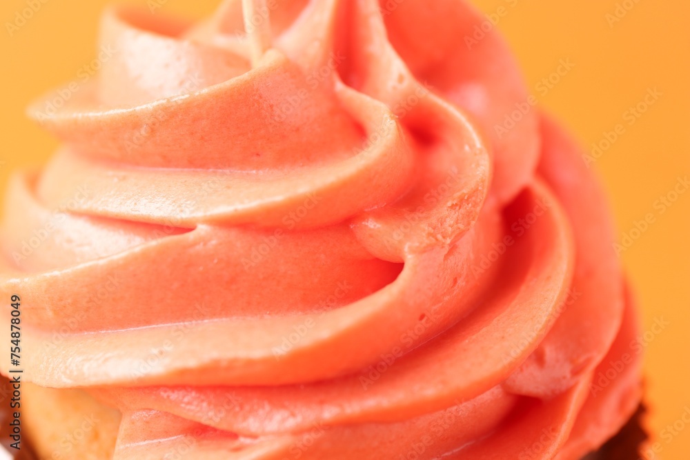 Delicious cupcake with bright cream on orange background, closeup