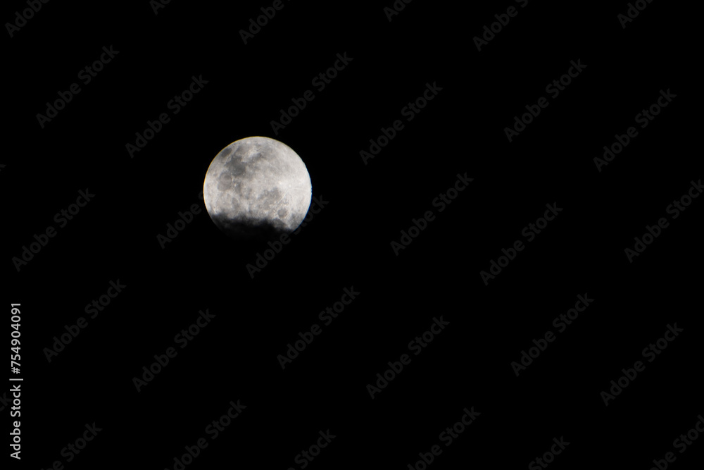 Clouds covering the full moon in the dark sky. Showing the Details of Lunar Surface in the Night. Clouds covering the full moon in the dark sky. Showing the Details of Lunar Surface in the Night.