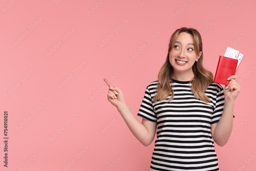 Happy young woman with passport and ticket pointing at something on pink background, space for text Happy young woman with passport and ticket pointing at something on pink background, space for text